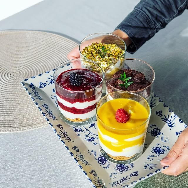 Quattro dessert in bicchiere: frutti rossi, pistacchio, tiramisù, mango